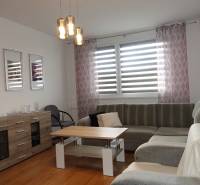 A bright living room with a corner sofa, a coffee table, and a sideboard in a three-room apartment.