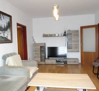 Living room of a 3-room apartment with a comfortable sofa, furniture with a wooden decor, and a television.
