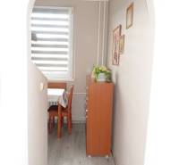 A hallway with an arched entrance and a wooden decor floor leads to the dining room in a 3-room apartment.