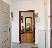 A hallway in a 3-room apartment with a wood-patterned floor and an intercom.
