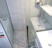 A bathroom with a shower and a washing machine in a 3-room apartment.