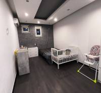 Children's room in a family house with a wooden decor floor and a wall with stone cladding.