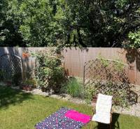 Garden of a 4-room apartment in Bratislava - Vrakuňa with a chair and a carpet on the grass.