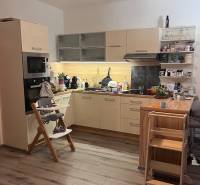 A kitchen in a 4-room apartment with a wooden decor floor, a child's chair, and toys.