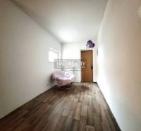 A room in a family house with an armchair and a wooden-patterned floor.