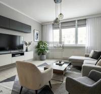 Living room in a 3-room apartment with a large sofa, TV, carpet, and wooden decor flooring.