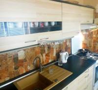 A room in a 2-room apartment with a wooden decor floor, a television, and built-in wardrobes.