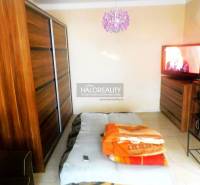 A bedroom in a two-room apartment with a bed, sofa, and cabinet with a wooden decor.