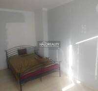 A bedroom with a metal bed and white walls in a two-room apartment.