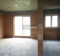 An unfinished interior of a family house with large windows and incomplete walls.