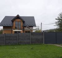 A family house in Sady nad Torysou with a dark roof and a concrete fence.