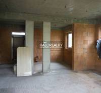 An unfinished interior in a family house with exposed brick walls and concrete floors.