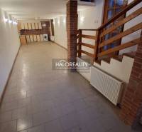 Interior in a family house with tiles, wooden staircase, and kitchen unit.
