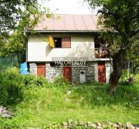 A cozy cottage surrounded by lush greenery and trees in a natural setting.