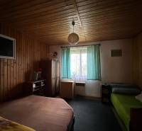 A room with wooden paneling and beds in a family house.