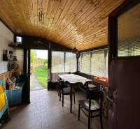Interior of a family house with a wooden decor floor, dining table, and a view of the garden.