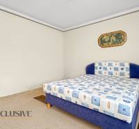 Bedroom with a blue bed, patterned blanket, and decorative painting in a family house.