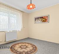 A room in a family house with a light carpet, curtains, and a wall painting.