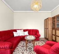 Red sofa set, table, display cabinet, and chandelier in a family house on a floor with a wooden decor.