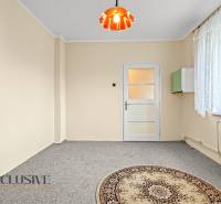 A bright room in a family house with a carpet and a window with a lace curtain.
