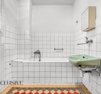 Bathroom in a family house with a rectangular bathtub, green sink, and striking tiles.