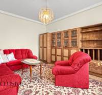 Living room of a family house with a red sofa set and wooden furniture.