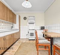 A kitchen in a family house with a kitchen unit, a table, and retro tiles on the walls.