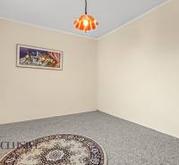 A room in a family house with a carpet, curtain, painting, and chandelier on the ceiling.