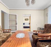 A family house with a living room, floral furniture, a coffee table, and a painting on the wall.