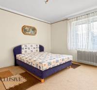 Bedroom in a family house with carpet, large window, and radiator.