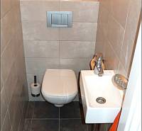 Small bathroom with a toilet and a sink in a 4-room apartment. Gray tiles and flooring.