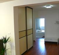 Interior of a 4-room apartment with a wooden decor floor and entrance to the bedroom.