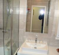 A bathroom with a shower, mirror, and sink in a 4-room apartment.