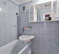 A bathroom with a bathtub and white tiles in a 2-room apartment.