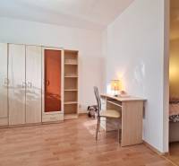 Wooden floor decor, wardrobe, desk, and bed in a 2-room apartment.