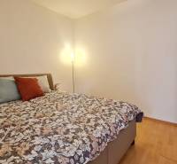 Bedroom in a 2-room apartment with a bed, lamp, and wooden decor flooring.