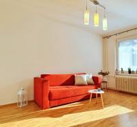 Living room with a red sofa, a coffee table, and a wooden decor floor in a two-room apartment.