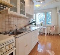 A kitchen in a 2-room apartment with a wooden decor floor and a dining table.
