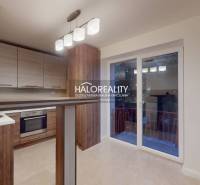 A kitchen in a 2-room apartment with a wooden decor floor and access to a balcony.