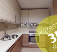 A kitchen in a 2-room apartment with a wooden decor floor and built-in cabinets.