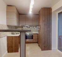 A kitchen unit in a 2-room apartment with a wooden decor floor and balcony doors.