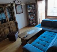Living room with a blue sofa, wooden sideboard, and wood-patterned flooring.