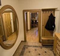 A hallway with a wooden decor floor, a mirror, and stylish furniture in a 3-room apartment.