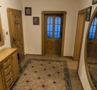 A hallway in a 3-room apartment with a mirror, tiles, and wooden furniture.