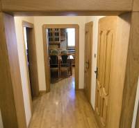 A hallway in a 3-room apartment with a wooden decor floor and coat hooks.