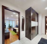 A hallway of a 3-room apartment with a wooden decor floor and stone cladding on the wall.
