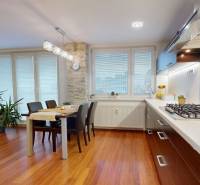 A kitchen in a 3-room apartment with a wooden decor floor, a dining table, and plants.