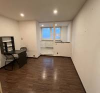 A room in a one-room apartment with a wooden decor floor and a table.
