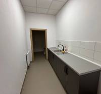 A narrow office with a kitchenette, gray tiles, and a sink.