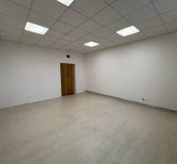 Empty room in offices with wood-patterned flooring and white walls.